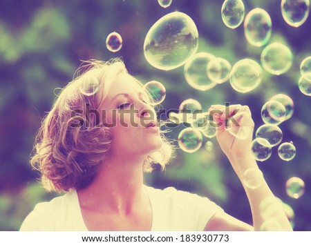 a pretty girl blowing bubbles - vintage toned with a retro instagram filter
