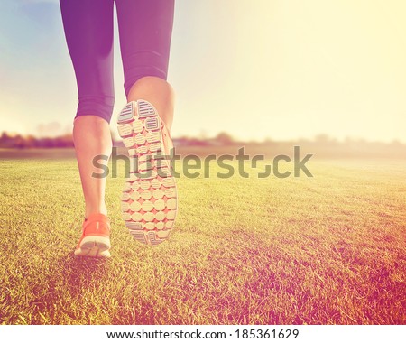 an athletic pair of legs on grass during sunrise or sunset - done with a soft vintage instagram like filter