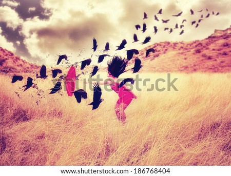 a girl in a field with an umbrella pointing toward a flock of birds done with a warm filter