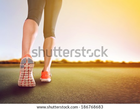 a woman with an athletic pair of legs going for a jog or run during sunrise or sunset - healthy lifestyle concept done with an instagram like filter