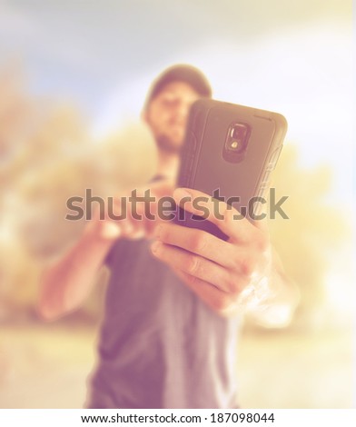 a young man using a cell phone to send a text message or make a phone call or browse the internet, done with a creative instagram like filter