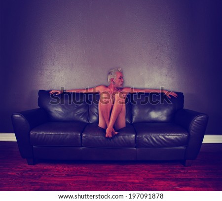 a young male sitting down on a brown leather couch