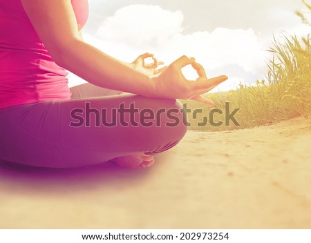 hands of a woman meditating in a yoga pose on the beach done with an instagram like filter