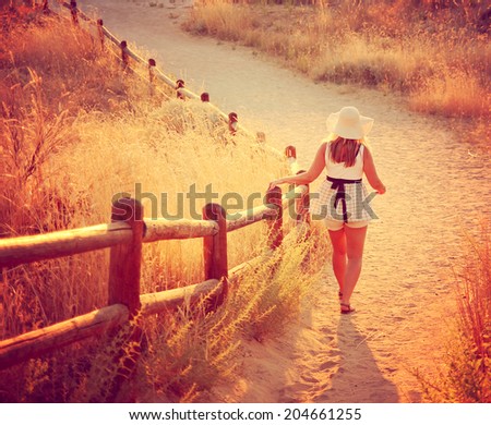 a woman walking on a path during sunset or sunrise toned with an instagram like filter