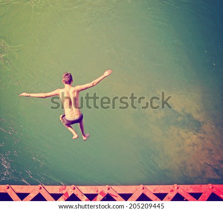 a boy jumping of an old train trestle bridge into a river done