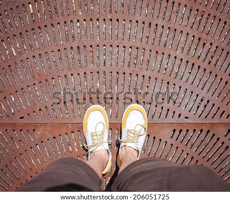 a shot of yellow and white boat or deck shoes on a rusty grate