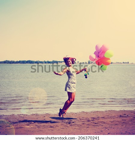 a pretty woman enjoying summer outside with a bunch of balloons toned with a retro vintage instagram filter