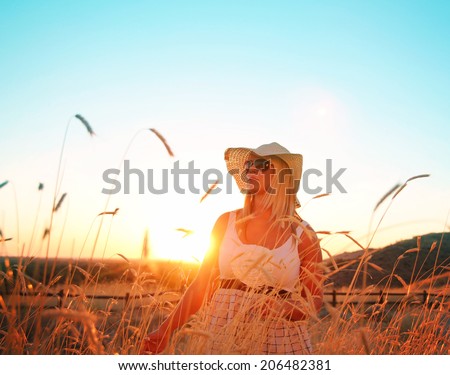 a pretty woman standing in a field at sunrise or sunset