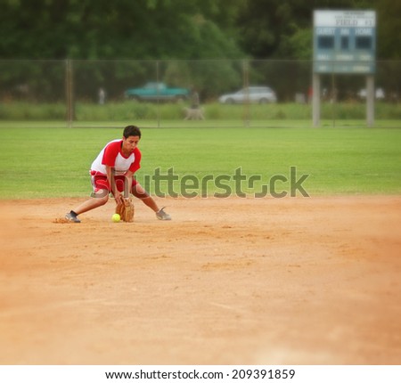 a woman squatting down to catch a grounder in a softball game