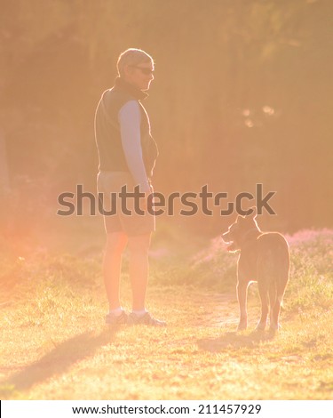 a woman walking with her dog at sunset or sunrise toned with a retro vintage instagram filter