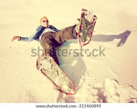 a woman playing in the snow with snow shoes on toned with a retro vintage instagram like filter