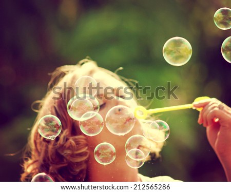 a pretty girl blowing bubbles toned with a retro vintage instagram filter effect
