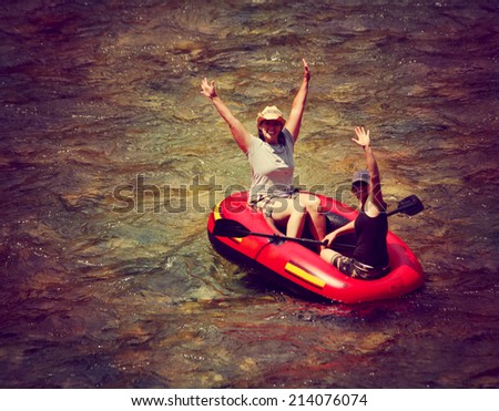 two girls floating down a river in an inflatable raft toned with a retro vintage instagram filter effect