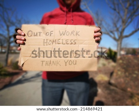 a begging homeless person with a sign on a cold sunny winter day