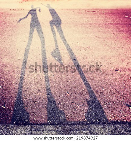 shadow of two people play fighting in the street toned with a retro vintage instagram filter (extremely grainy filter used)