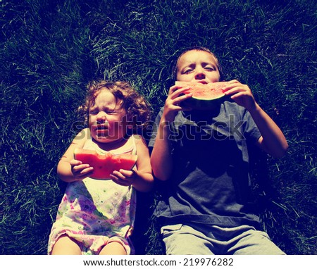 two kids eating watermelon toned with a retro vintage instagram filter effect