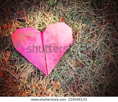 an origami heart on grass with sun spots shining on it toned with a retro vintage instagram filter (shallow depth of field)