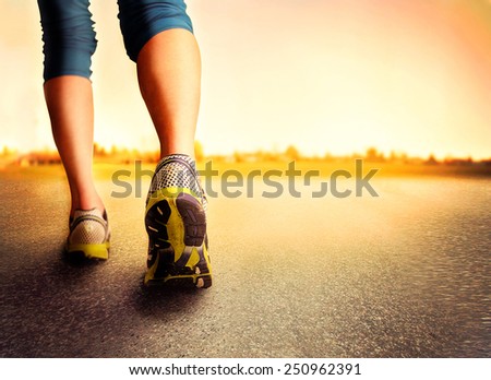 an athletic pair of legs on pavement during sunrise or sunset - healthy lifestyle concept