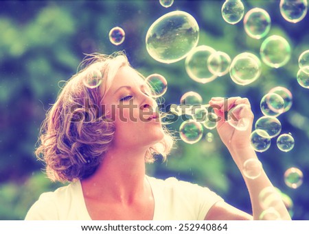 a beautiful woman blowing bubbles toned with a retro vintage instagram filter effect app or action