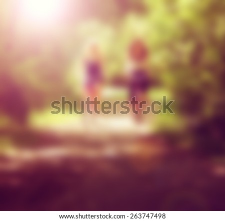 two girls riding bikes on a path in a park full of trees done with a retro vintage instagram filter effect app or action and blurred out so text can be place over the image