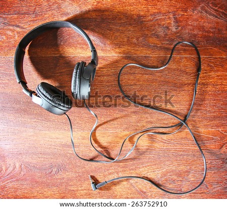 headphones and the cord in the shape of a heart symbolic of a love for music on an antique wooden texture background