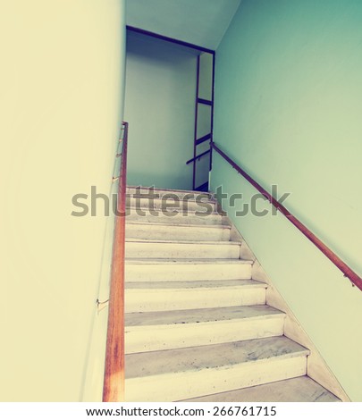 an empty stairwell with a wooden hand rail toned with a retro vintage instagram filter effect app or action