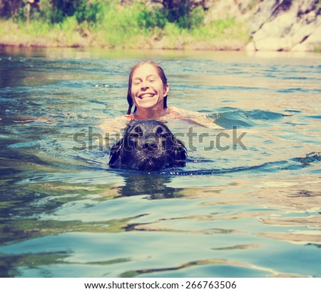 a girl and a big lab dog swimming in the water toned with a retro vintage instagram filter effect app or action