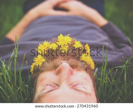 a sleeping hipster lying in tall grass with dandelions in his epic beard taking a nap toned with a retro vintage instagram filter and light leaks