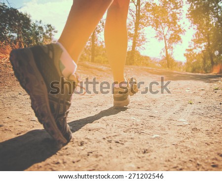 an athletic pair of legs running or jogging on a path during sunrise or sunset toned with a retro vintage instagram filter effect app or action (focus on left foot)