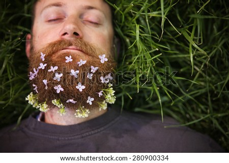 a sleeping hipster lying in tall grass with lilacs in his epic beard taking a nap toned with a retro vintage instagram filter and light leaks