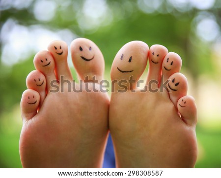 smiley faces on a pair of feet on all ten toes (VERY SHALLOW DOF - big toe on the right) in a park setting
