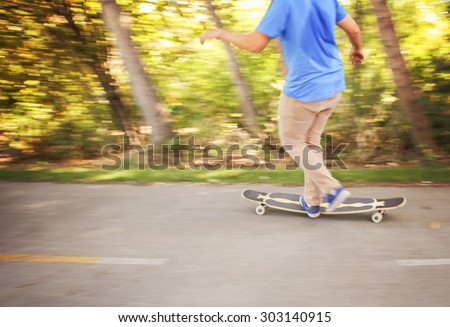 Motion blur of fast skateboarder with feet moving on a bike path in a natural and urban background