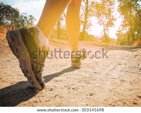 an athletic pair of legs running or jogging on a path during sunrise or sunset toned with a retro vintage instagram filter effect app or action