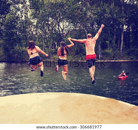 three people jumping off a concrete structure into a river toned with a retro vintage instagram filter effect app or action