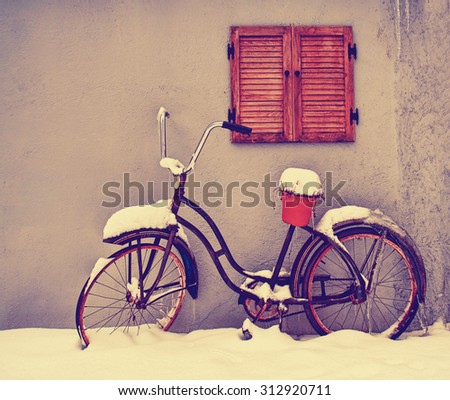 an antique bike with an empty pot on the seat in winter covered in snow toned with a retro vintage instagram filter app or action effect