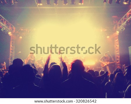 a crowd of people at a concert clapping their hands with a slight blur toned with a retro vintage instagram filter effect app or action