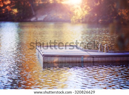 a serene view of a peaceful dock in a misty atmosphere on calm water during morning sunrise or evening sunset toned with a retro vintage instagram filter effect app or action