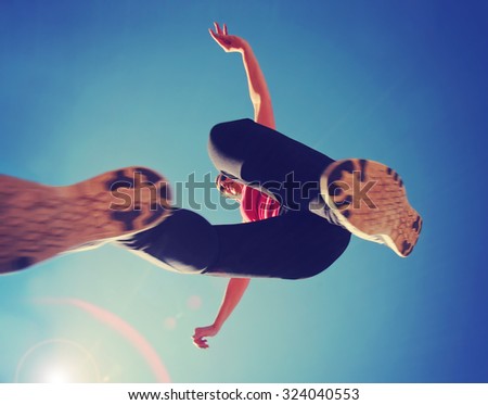 a woman dressed in active wear jumping directly over the camera with a wide angle lens during summer time with a lens flare in the corner - a unique perspective