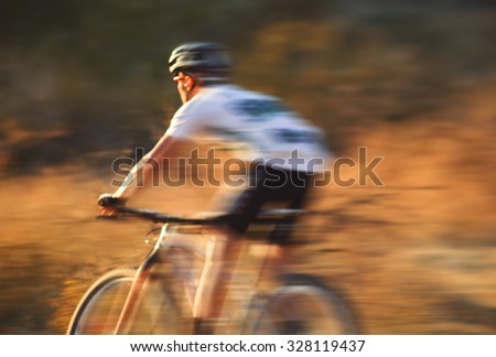 a man riding a bicycle down a dirt trail in the back country to get away from the city toned with a retro vintage instagram filter app or action effect