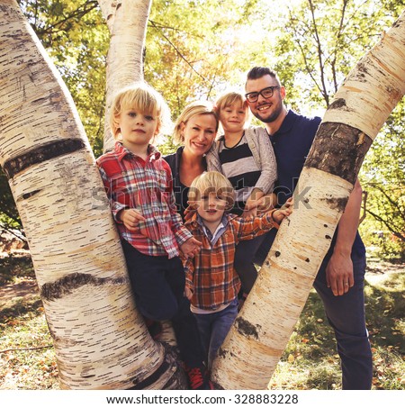 a cute family posing on a tree in a park toned with a retro vintage instagram filter effect app or action