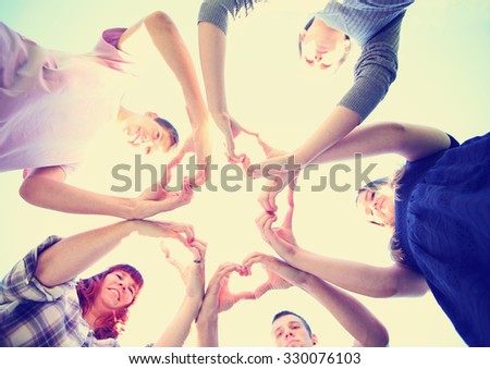 a group of people with their hands in a circle making heart shapes toned with a retro vintage instagram filter app or action effect