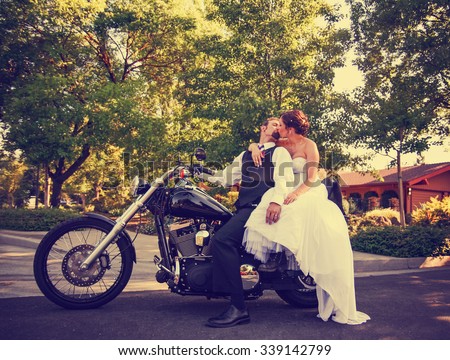 a couple on their wedding day on a black motorcycle in an urban neighborhood toned with a retro vintage instagram filter app or action effect