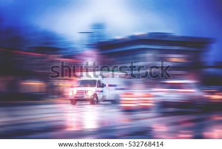 an ambulance racing through the rain on a stormy night with motion blur (NO SHARP FOCUS DUE TO RAIN) with reflections in the road