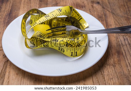 Ruler in a plate on wood table as concept of diet