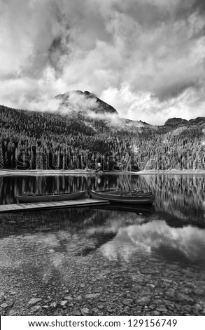 Reflection in water of mountain lakes and boats black and white