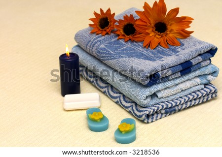 Natural bath soap, folded towels, candle and flowers.