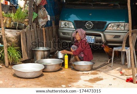 SUBURB SIHANOUKVILLE, CAMBODIA. FEBRUARY 26, 2013 - An elderly woman washes the dishes on the street