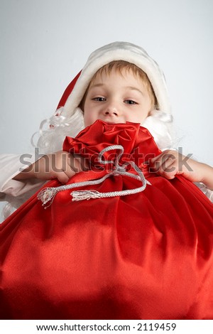 small boy with santa\'s hat and bag full of gifts
