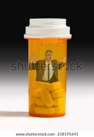 Man trapped inside of a pain pill bottle which illustrates pharmeceutical pill addiction.