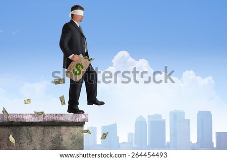 Blindfolded business man with bag of money is about to walk off the edge of a building representing financial risk, management, planning, investments, savings, and many other financial concepts.